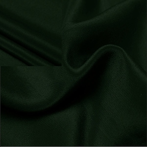 Pode incluir: Um close-up de um tecido verde escuro com uma textura lisa e sedosa. O tecido está drapeado e dobrado, criando curvas e dobras suaves.