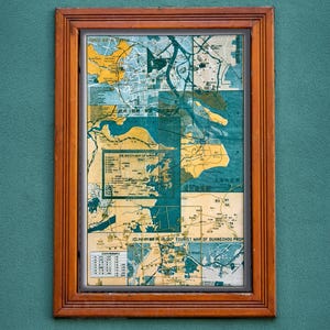 May include: A framed vintage map of Guangzhou, China, in shades of blue, yellow, and beige. The map is divided into sections, with text in English and Chinese. The wooden frame adds a classic touch to the artwork.