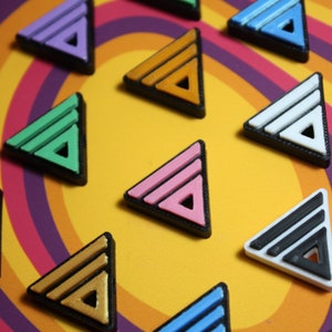 May include: Nine colorful triangle-shaped stickers with a double line design. The stickers are arranged in a circle on a multi-colored background.