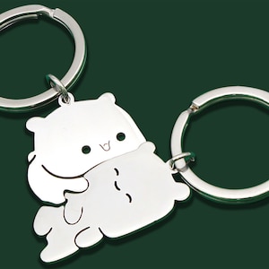 Peut inclure: Deux porte-clés argentés avec un joli motif d'ours. Chaque porte-clés est orné d'un anneau rond pour attacher les clés. Le motif de l'ours est une forme stylisée et dessinée avec un visage souriant. Les porte-clés sont en métal brillant.