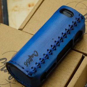 Puede incluir: Una funda de cuero azul con un diseño cosido y el texto "Crafts66". La funda está diseñada para guardar un dispositivo electrónico. La funda está sobre una caja de cartón.