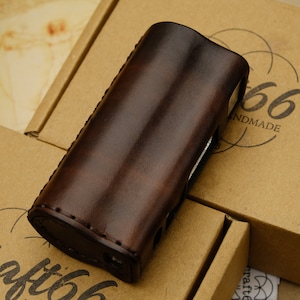 May include: A brown leather case with stitching detail. The case is sitting on a brown cardboard box with the text "Craft66 Handmade" printed on it.