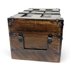 May include: A wooden chest with dark brown stain, metal accents, and a handle. The chest has metal bands and corner protectors. The top has wooden slats. The chest is likely used for storage or decoration.