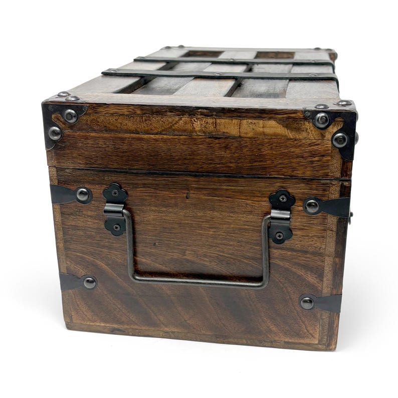 May include: A wooden chest with dark brown stain, metal accents, and a handle. The chest has metal bands and corner protectors. The top has wooden slats. The chest is likely used for storage or decoration.