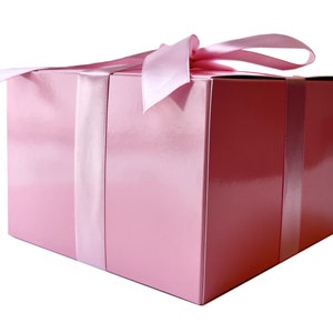 May include: A pink gift box with a satin ribbon tied in a bow. The box is wrapped in a shiny pink paper.