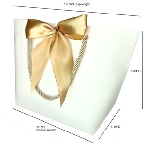 May include: White gift bag with a gold satin bow and rope handles. The bag measures 10.5 inches long at the top, 7.5 inches long at the bottom, 3.5 inches deep, and 7.75 inches high. Ideal for gifts and special occasions.