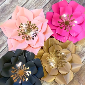 May include: Four large paper flowers with gold centers. The flowers are pink, black, brown, and hot pink.