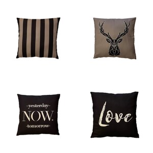 Puede incluir: Cuatro almohadas decorativas con diferentes diseños. La primera almohada tiene rayas negras y marrones. La segunda almohada tiene un diseño de ciervo geométrico en negro sobre un fondo beige. La tercera almohada tiene las palabras "yesterday NOW tomorrow" en blanco sobre un fondo negro. La cuarta almohada tiene la palabra "Love" en blanco sobre un fondo negro.