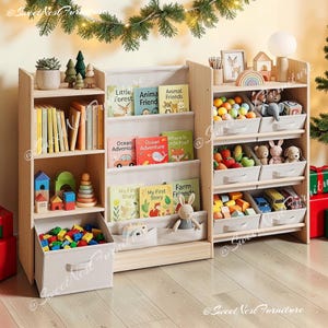 May include: A light wood children's storage unit featuring a central fabric book display, a left-side shelving section with a bottom fabric bin, and a right-side section with six angled fabric storage bins filled with various toys and books.