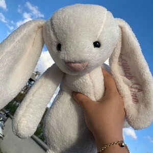 May include: White plush bunny with long ears, one ear is embroidered with the name "Leigha Grace".