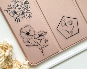 May include: Four clear stickers with black line drawings of flowers on a pink surface. The stickers feature different floral arrangements, including a bouquet, a single flower, and two flowers in a hexagonal frame. The text "Made with Love" appears on each sticker.