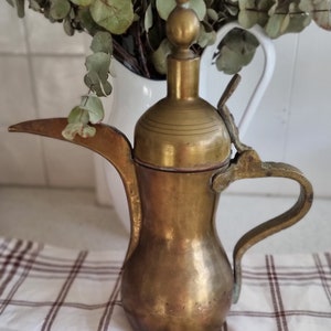 May include: A vintage brass teapot with a decorative lid and a handle. The teapot is a traditional design with a rounded body and a spout.