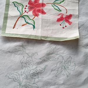 Puede incluir: Una hoja de patrón de bordado Semco Special Design SX102 con una ilustración impresa de dos lirios rosas con hojas y tallos verdes, colocada sobre una tela blanca con un contorno verde a juego del mismo diseño floral.