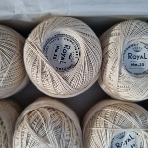 May include: Six balls of white cotton yarn with the label "Cordonnet Royal Special Nm.30" on each ball.