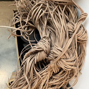 May include: A large pile of brown suede leather cord, likely for crafting or jewelry making.