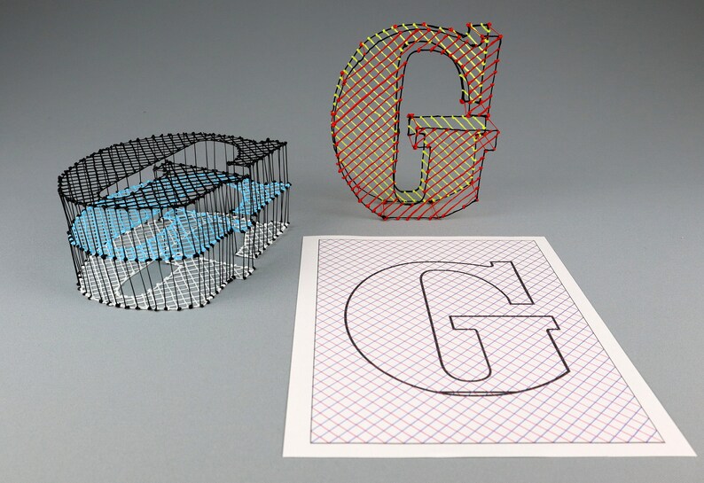 May include: Three dimensional string art of the letter G. The first G is made with black string on a white grid, the second G is made with red and yellow string on a white grid, and the third G is a black outline on a white grid with red and blue lines.