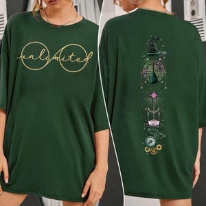 May include: Green oversized t-shirt with the word "unlimited" in gold lettering on the front and a graphic of a witch's hat, broom, moon, and stars on the back.