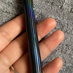 Op de afbeelding: Een zwarte laserpointer met een gouden top en regenboogkleurige strepen.