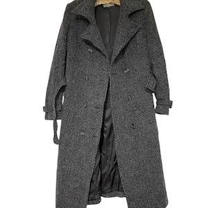May include: A long, double-breasted coat in a dark gray and black houndstooth pattern. The coat features a notched collar, button closures, and a matching belt. The interior lining is black. The sleeves have adjustable cuffs.