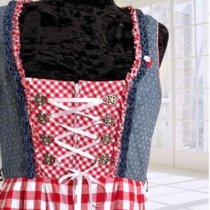 May include: A red and white gingham dirndl dress with a blue denim bodice and white lace trim. The bodice has a zipper closure and a white ribbon lacing detail with silver metal accents.