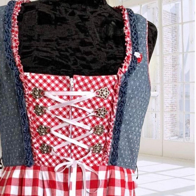 May include: A red and white gingham dirndl dress with a blue denim bodice and white lace trim. The bodice has a zipper closure and a white ribbon lacing detail with silver metal accents.