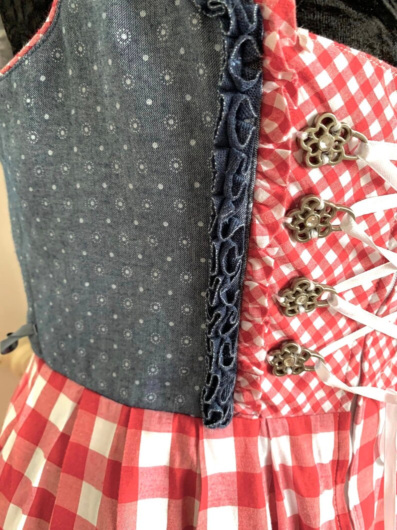 May include: A red and white gingham dress with a blue denim bodice and white lace-up detail. The bodice has a white polka dot pattern.