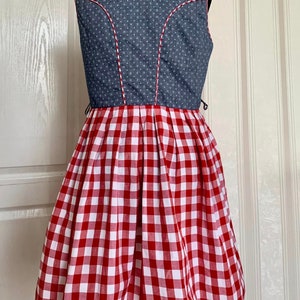 May include: A sleeveless dress with a blue denim bodice and a red and white gingham skirt. The bodice has white polka dots and a white trim around the neckline.