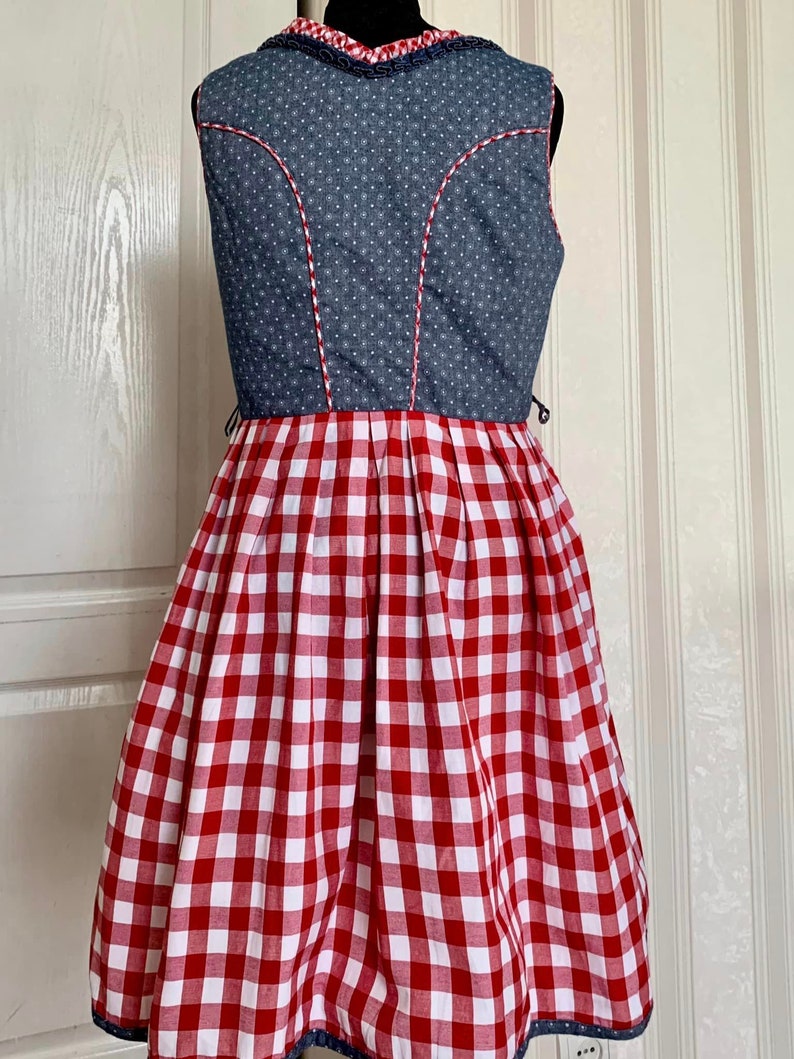 May include: A sleeveless dress with a blue denim bodice and a red and white gingham skirt. The bodice has white polka dots and a white trim around the neckline.