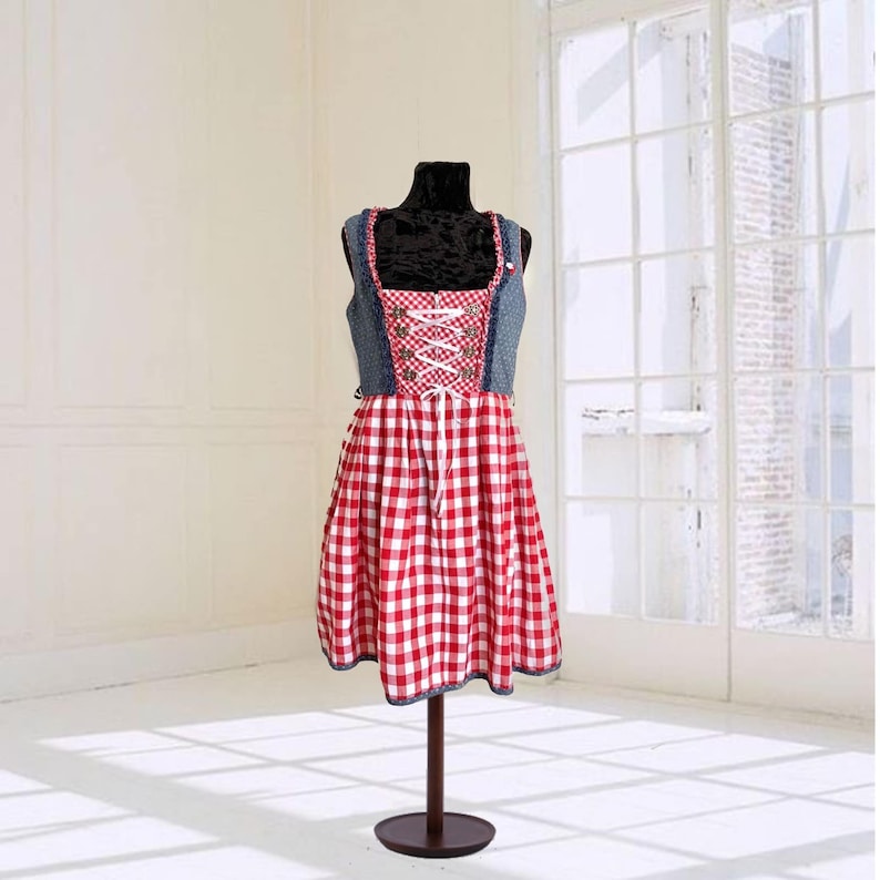 May include: A red and white gingham dress with a denim bodice and white lacing. The dress is on a mannequin and has a sleeveless design.