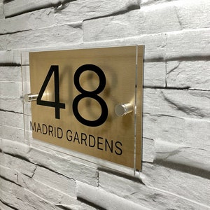 May include: Gold acrylic house number sign with black numbers and text. The sign reads "48. MADRID GARDENS".