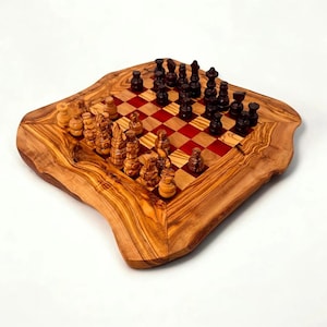 Op de afbeelding: Een handgemaakt schaakspel met een houten bord met een natuurlijke rand en een rood en bruin geblokt speeloppervlak. De schaakstukken zijn uit hout gesneden en op het bord geplaatst.