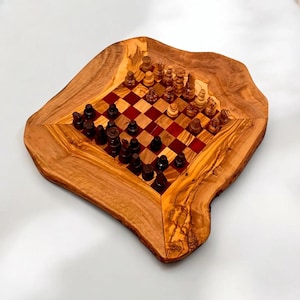 Op de afbeelding: Een houten schaakspel met een natuurlijke rand. Het schaakbord heeft een rood-bruin geblokt patroon. De schaakstukken zijn bruin en beige. De set wordt gepresenteerd op een wit oppervlak.