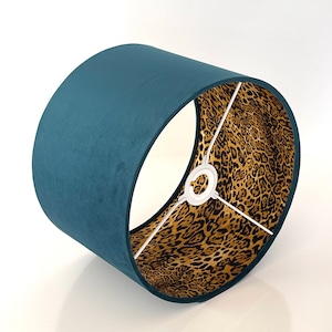 Può includere: Paralume in velluto blu petrolio con fodera a stampa leopardata. Il paralume è rotondo e ha un anello di metallo bianco nella parte superiore.