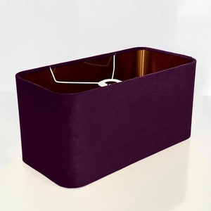 May include: A rectangular lampshade in a deep purple color. The shade is made of fabric and has a smooth, even texture.