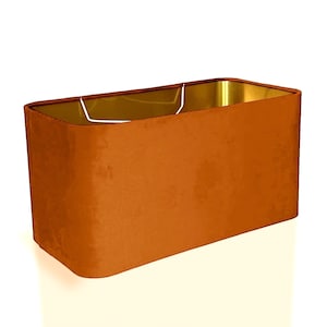 Pode incluir: Um abajur retangular de cor castanho escuro. O abajur é feito de tecido e tem um forro dourado.