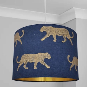 Può includere: Un paralume blu navy con un motivo a stampa di leopardo dorato metallizzato. Il paralume ha un bordo dorato attorno al bordo inferiore.