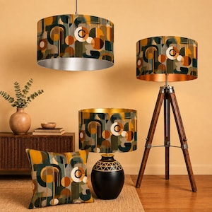 May include: A collection of home decor items featuring a matching geometric pattern in shades of orange, dark green, and cream. The set includes a hanging pendant light, a tripod floor lamp, a table lamp with a black base, and a square throw pillow.