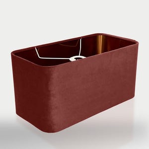 May include: A rectangular lampshade made of a deep red velvet fabric. The shade has a white metal frame and is designed for a standard light bulb.