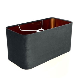 May include: A dark gray rectangular lampshade made of fabric. The shade has a copper-colored lining.