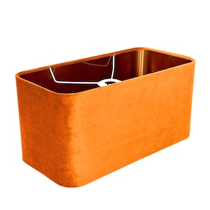 Könnte beinhalten: Ein rechteckiger Lampenschirm aus orangefarbenem Samt mit einem weißen Kabel.