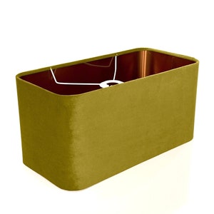 May include: A rectangular lampshade in a muted olive green color. The shade is made of a soft, velvety fabric.