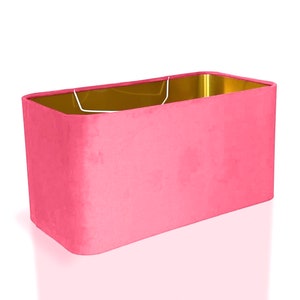 May include: A rectangular pink lampshade with a gold interior. The lampshade is made of fabric and has a smooth, even texture.