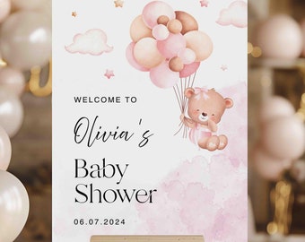 May include: A pink and white baby shower welcome sign with a teddy bear holding balloons. The sign says "Welcome to Olivia's Baby Shower 06.07.2024".