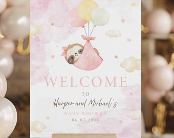 May include: A baby shower welcome sign on an easel. The sign features a watercolor design with a sloth in a pink blanket carried by balloons. The text reads "Welcome to Harper and Michael's Baby Shower 06.07.2024."