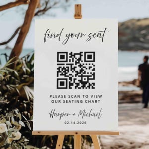 May include: A white sign on a wooden easel with the text "find your seat" in elegant script. Below is a QR code and the text "PLEASE SCAN TO VIEW OUR SEATING CHART". The names "Harper + Michael" and the date "02.14.2026" are also displayed.
