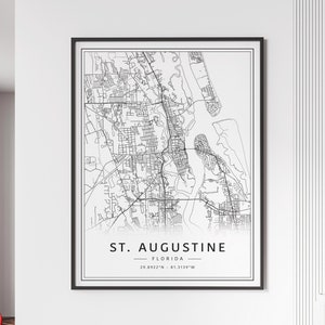 May include: Black and white line art map of St. Augustine, Florida. The map shows the city's streets, waterways, and coastline. The text "ST. AUGUSTINE - FLORIDA - 29.8922°N - 81.3139°W" is printed below the map.