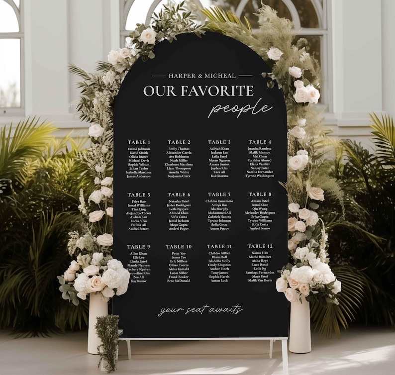 May include: Black wedding seating chart with white text. The chart is shaped like an arch and has the text "HARPER & MICHEAL OUR FAVORITE people" at the top. The chart lists tables 1 through 12 with guest names.