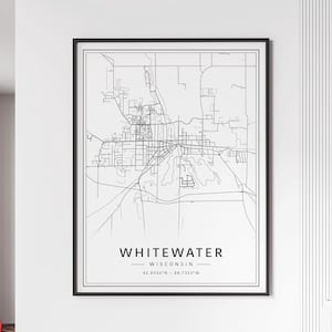 May include: A black and white framed map print of Whitewater, Wisconsin. The map features detailed street layouts and geographical features. The city name and coordinates are printed at the bottom.