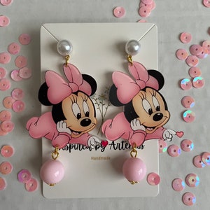 May include: Pink and black Minnie Mouse character earrings with a pink pearl dangle. The earrings are handmade and feature a gold-colored metal.