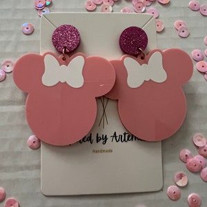 Puede incluir: Pendientes de rat&oacute;n de color rosa y blanco con un acento de purpurina rosa. Los pendientes est&aacute;n hechos a mano y se muestran en una tarjeta blanca con el texto "Made by Artem Handmade".